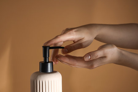 Hands with liquid soap on brown backgroundの写真素材