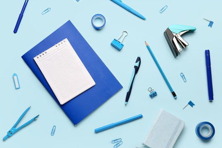 Composition with blank notebook and stationery supplies on blue backgroundの写真素材