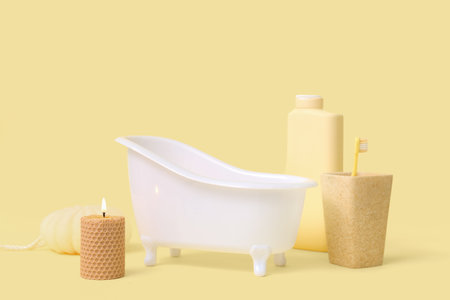 Small bathtub, burning candle and bath supplies on color backgroundの写真素材