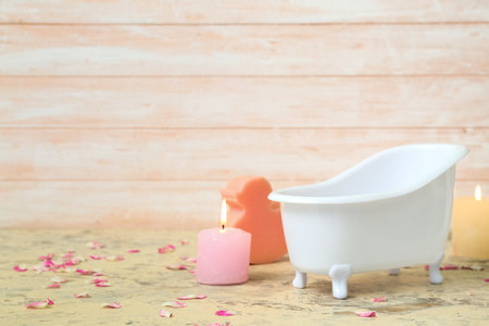 Small bathtub, burning candles, sponge and flower petals on tableの写真素材