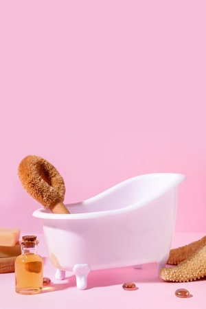 Small bathtub, massage brush and essential oil on pink backgroundの写真素材