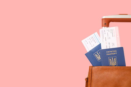 Bag with Ukrainian passports, tickets and suitcase on pink backgroundの写真素材