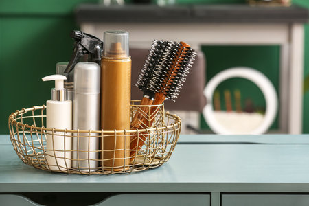Basket with different hair sprays and brushes on table in beauty salonの写真素材