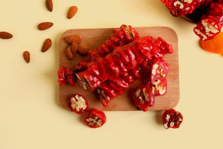 Wooden board with tasty churchkhela and almond nuts on color backgroundの写真素材