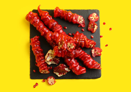 Slate board with tasty churchkhela and pomegranate on yellow backgroundの写真素材