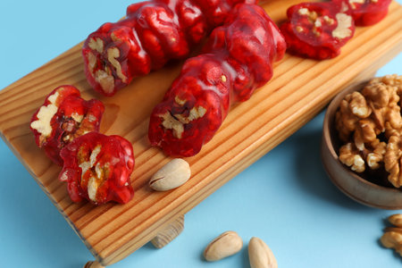 Wooden BOARD WITH tasty churchkhela and nuts on color background, closeupの写真素材