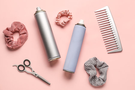 Bottles of hair sprays, comb, scrunchies and scissors on color backgroundの写真素材