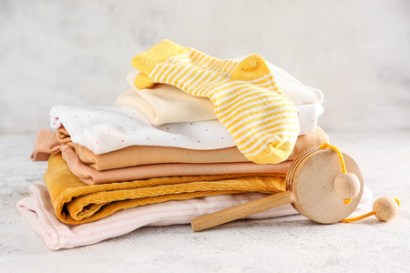 Stack of baby clothes and wooden toy on light backgroundの写真素材