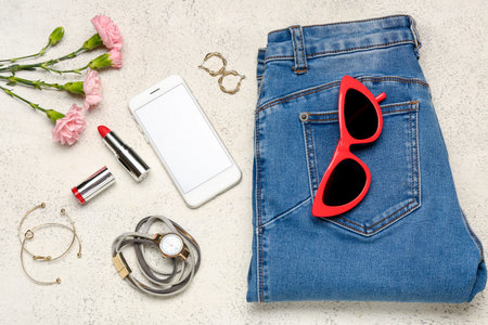 Composition with modern mobile phone, female accessories, clothes and carnation flowers on light...