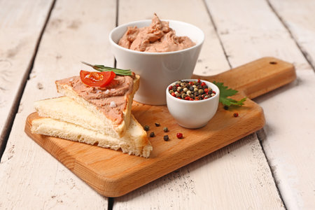 Board with bowl of tasty pate, sandwiches and peppercorns on light wooden backgroundの写真素材