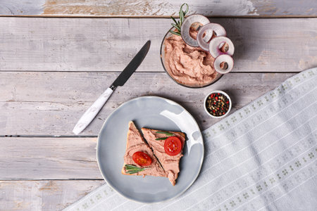 Bowl of delicious pate, sandwiches and peppercorns on light wooden backgroundの写真素材