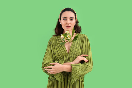 Young woman in dress with alstroemeria flowers on green backgroundの写真素材