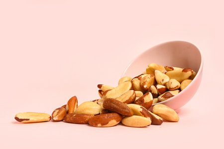 Overturned bowl of tasty Brazil nuts on pink backgroundの写真素材