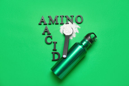 Text AMINO ACID , scoop with powder and bottle of water on green backgroundの写真素材