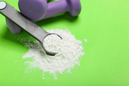 Scoop of amino acid supplement and dumbbells on color backgroundの写真素材