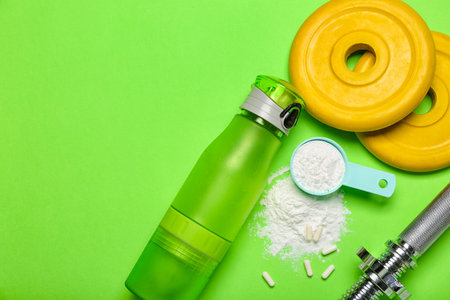 Scoop with amino acid supplement, bottle of water, barbell plates and grip on color backgroundの写真素材