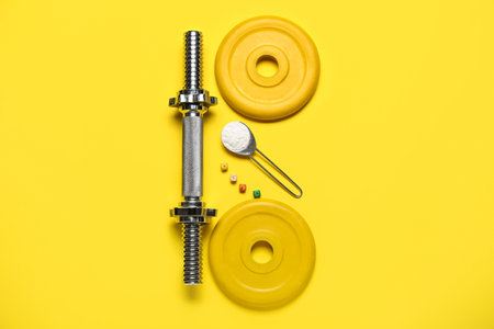 Barbell plates, grip and scoop of amino acid supplement on yellow backgroundの写真素材