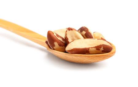 Wooden spoon with tasty Brazil nuts on white background, closeupの写真素材