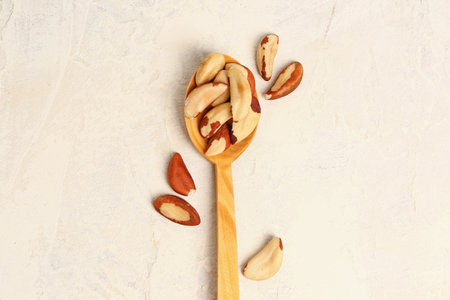 Wooden spoon with tasty Brazil nuts on light backgroundの写真素材