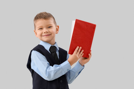 Cute little teacher with book on gray backgroundの写真素材