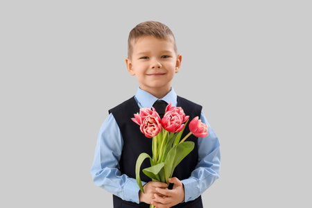 Cute little boy in suit with tulips on gray backgroundの写真素材