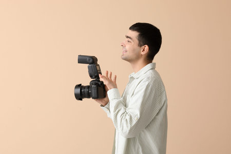 Young male photographer with professional camera on gray background