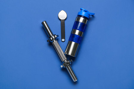Bottle of water, dumbbell and scoop with amino acid supplement on blue backgroundの写真素材