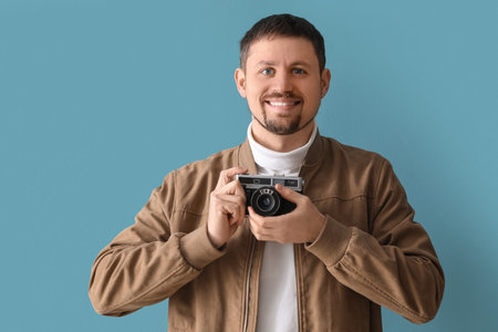 Male photographer with camera on blue backgroundの写真素材