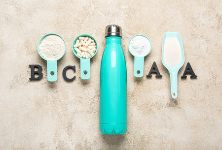 Composition with bottle of water, letters BCAA, amino acid pills and powder on grunge backgroundの写真素材