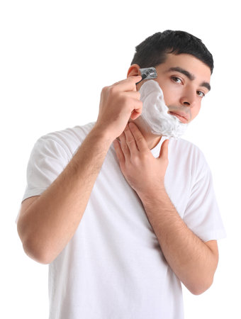 Young man shaving against white backgroundの写真素材