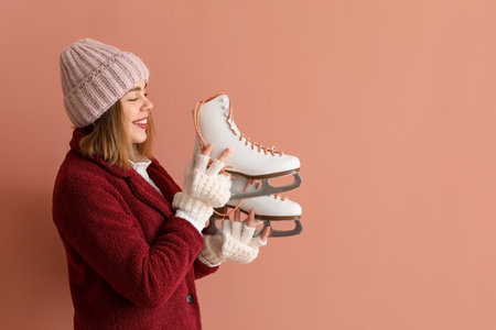 Pretty young woman with ice skates on pink backgroundの写真素材
