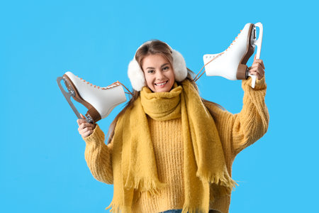 Pretty young woman with ice skates on blue backgroundの写真素材
