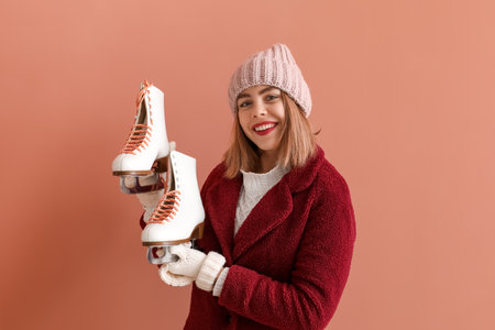 Pretty young woman with ice skates on pink backgroundの写真素材