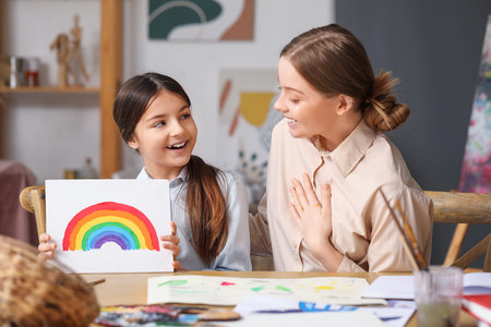 Little girl with painting and her drawing teacher in workshopの写真素材