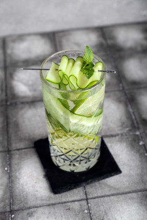 Glass of mojito with cucumber on tile tableの写真素材