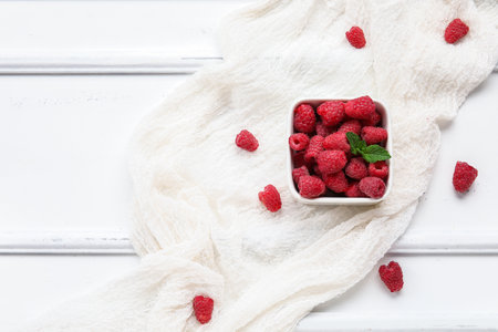 Bowl with fresh raspberry and mint on light wooden backgroundの写真素材