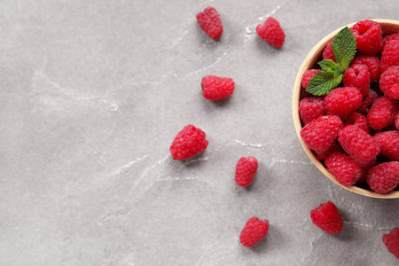 Bowl with fresh raspberry and mint on gray background, closeup