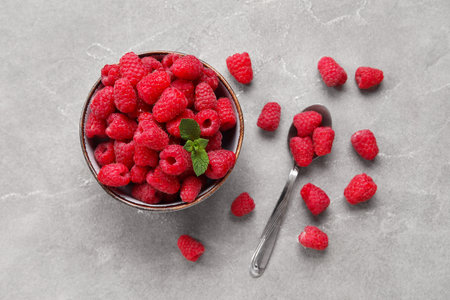 Bowl with fresh raspberry and spoon on gray backgroundの写真素材