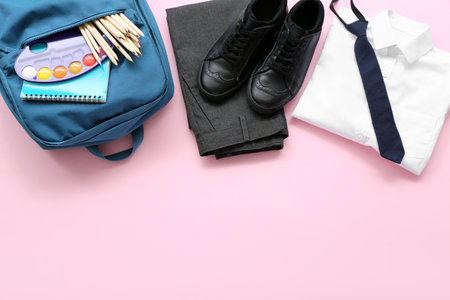 Stylish school uniform with backpack and stationery on pink backgroundの写真素材