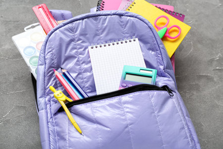 Backpack with blank notebook and stationery on grunge gray backgroundの写真素材