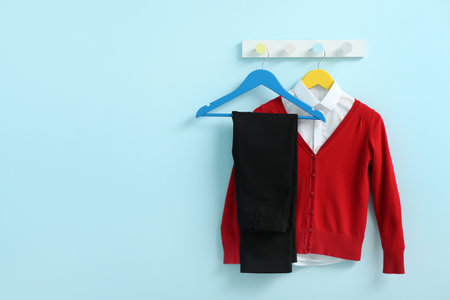 Stylish school uniform hanging on rack against blue wallの写真素材