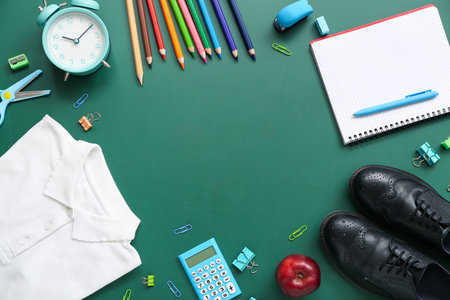 Frame made of stylish school uniform with alarm clock and different stationery on green chalkboardの写真素材
