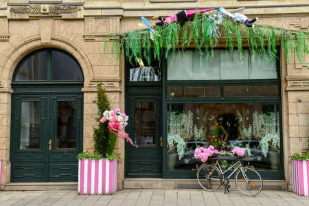 Stylish bicycle with peonies flowers near shop entrance on city streetの写真素材