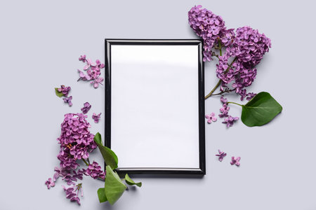Composition with beautiful lilac flowers and blank frame on light backgroundの写真素材