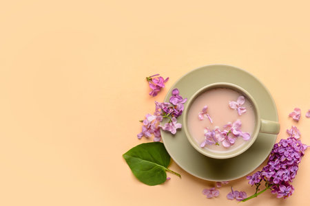 Cup of coffee and beautiful lilac flowers on beige backgroundの写真素材