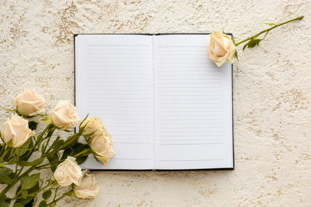 Blank open notebook and beautiful rose flowers on light backgroundの写真素材