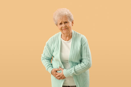 Senior woman with appendicitis on beige backgroundの写真素材