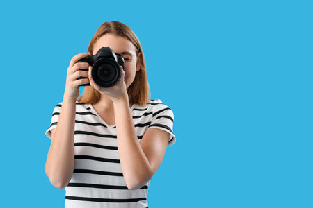 Female photographer with professional camera on blue backgroundの写真素材