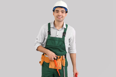 Young carpenter with tools on gray backgroundの写真素材