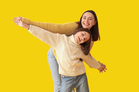 Little girl and her mother in knitted sweaters on yellow backgroundの写真素材